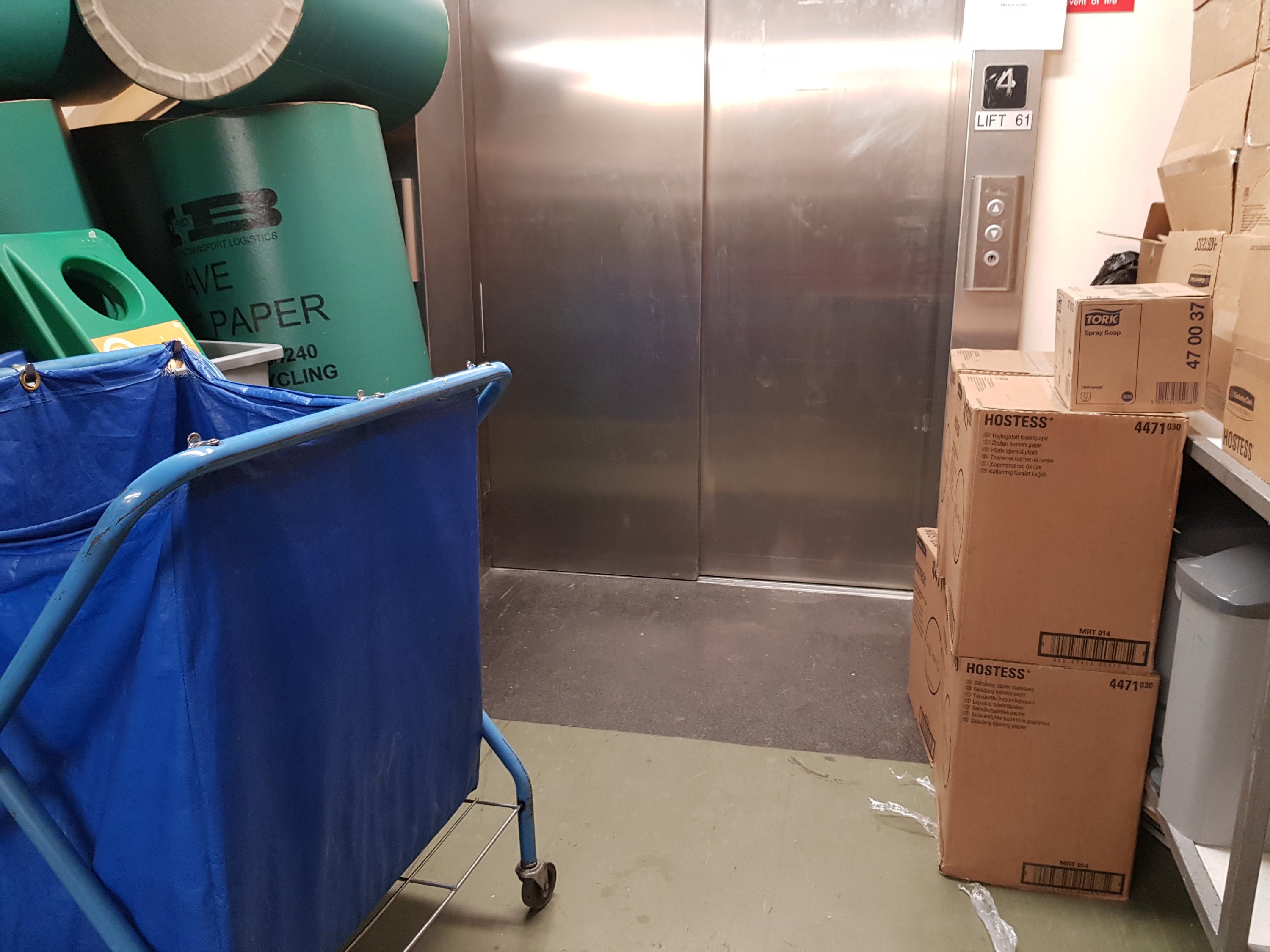 The lift blocked by crates, boxes, trolleys, & all manner of cleaning equipment.