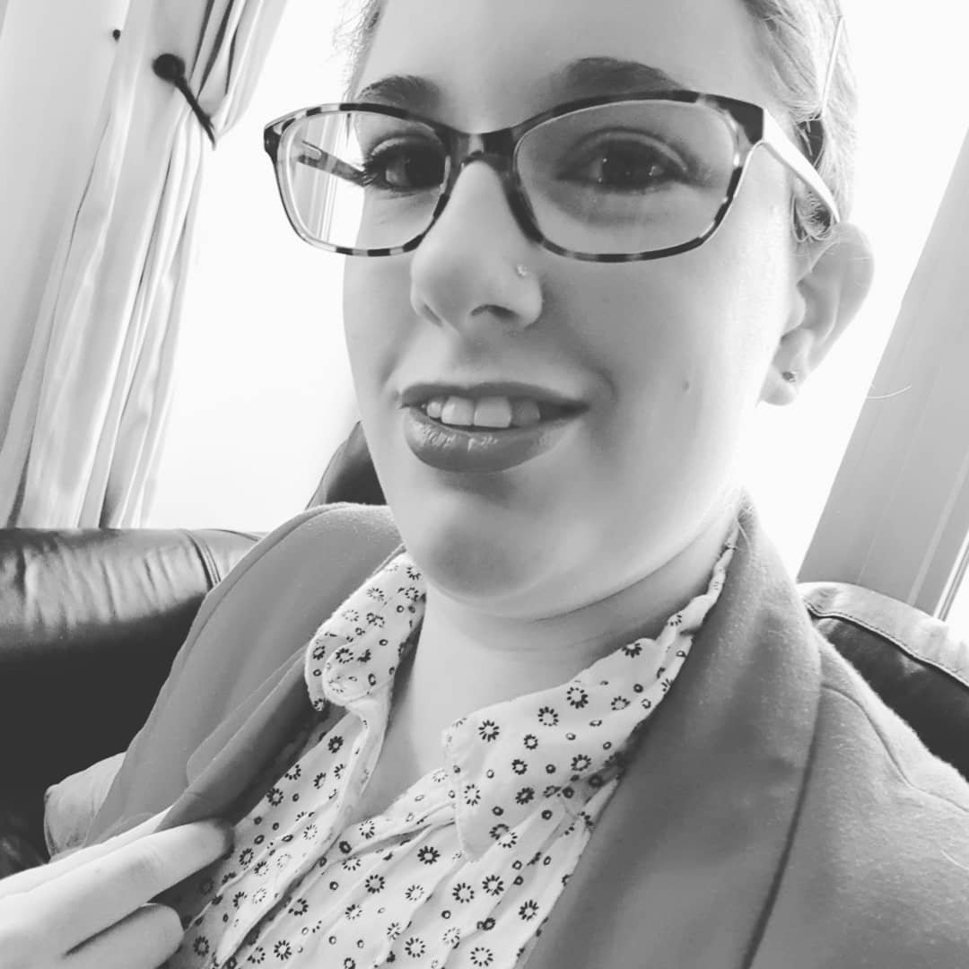 Black & white selfie. My hair is in a bun on the back of my head & I'm wearing light eye make-up & lipstick.