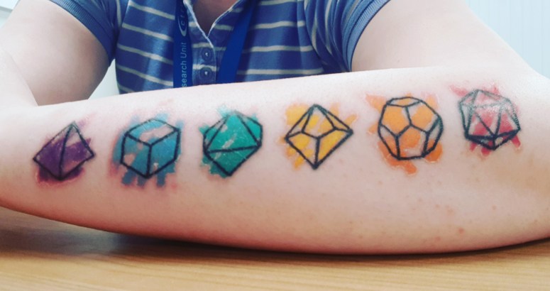 The outlines of Dungeons and Dragons dice from elbow to wrist in pride colours.