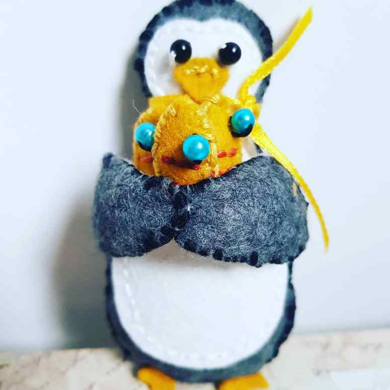Another felt penguin, this time carrying three fish.