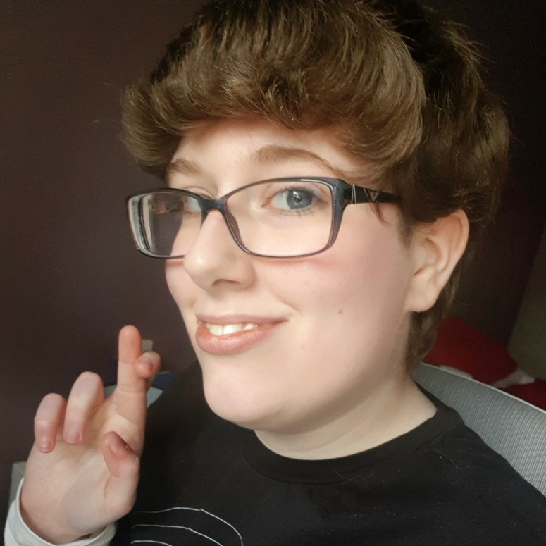 Selfie taken after submitting my job application. I'm wearing no makeup and a simple black t-shirt, and am holding up crossed fingers.