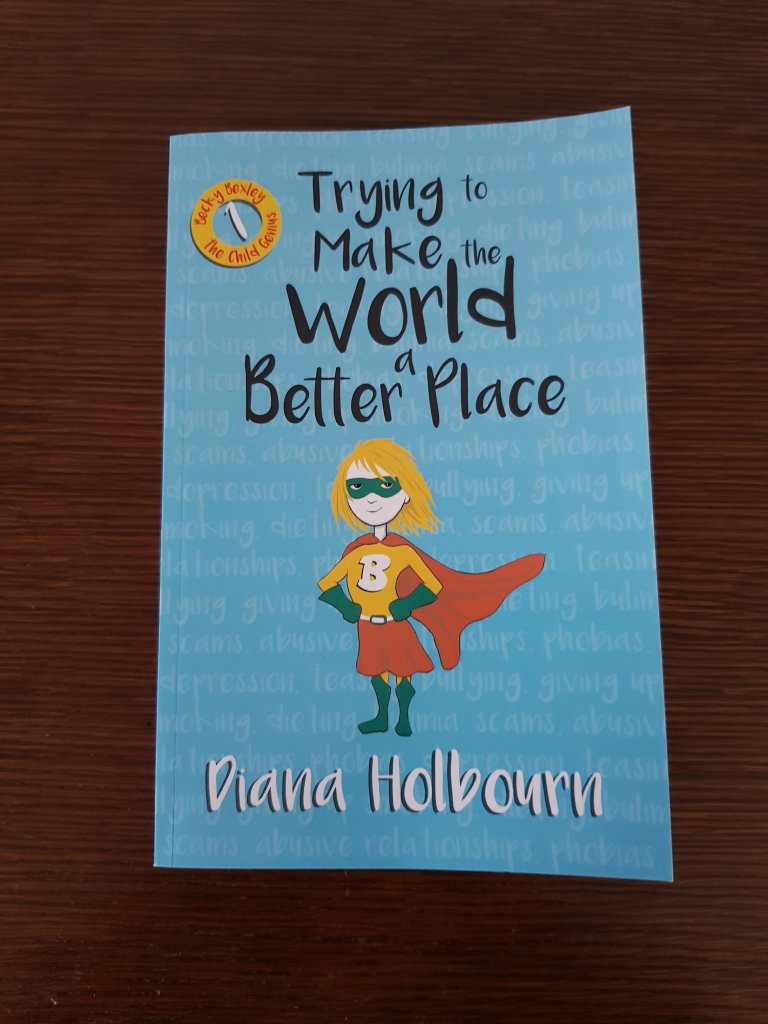 Book 1: Trying to make the world a better place. The book has a cartoon girl superhero in the centre of a bright blue cover.