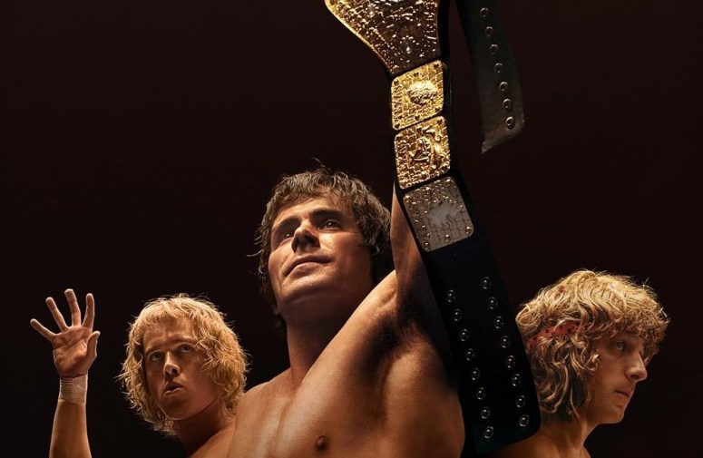 Three of the Von Erich brothers. On the left, David makes the gesture of the Iron Claw. In the foreground, Kevin holds up a black and gold championship belt. On the right, Kerry stands with his right side facing the camera.